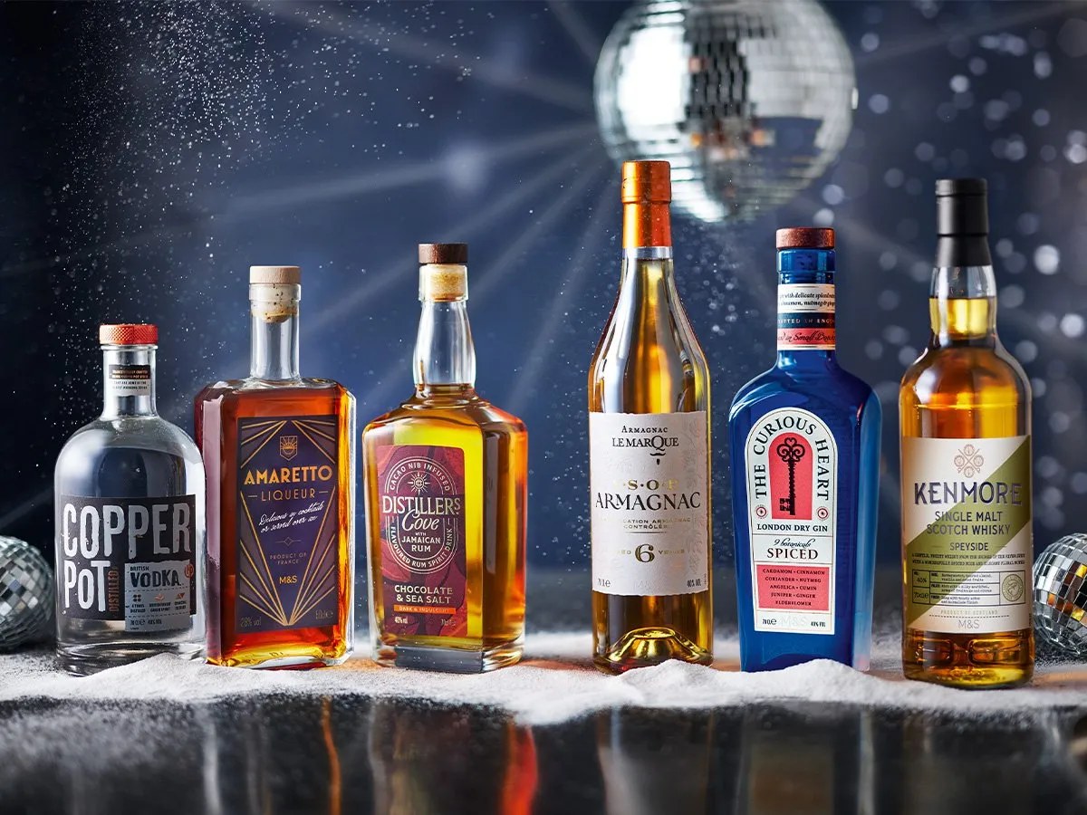 Bouteille de whisky français posée devant les alambics d'une distillerie artisanale