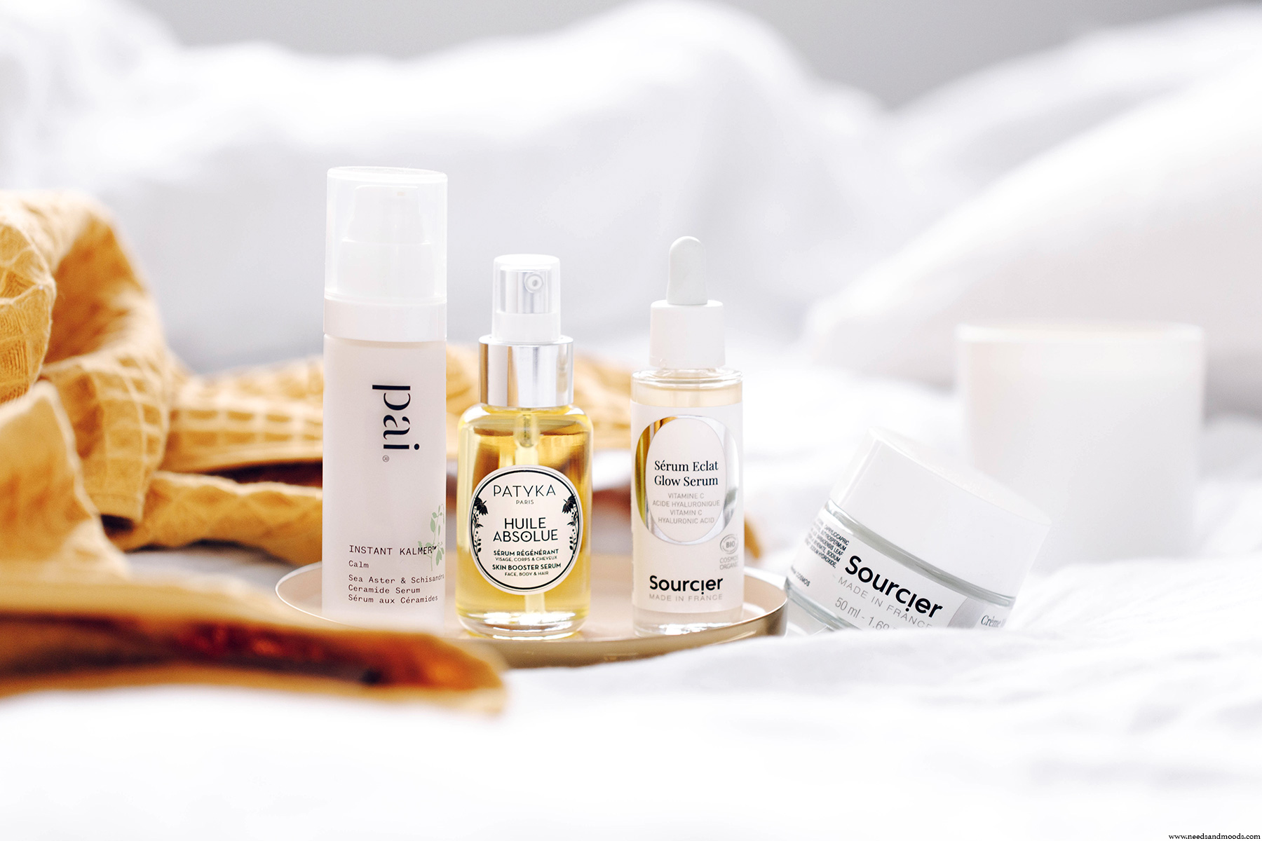 Flacons et pots de crèmes d'une marque de cosmétique bio française posés sur une table en bois